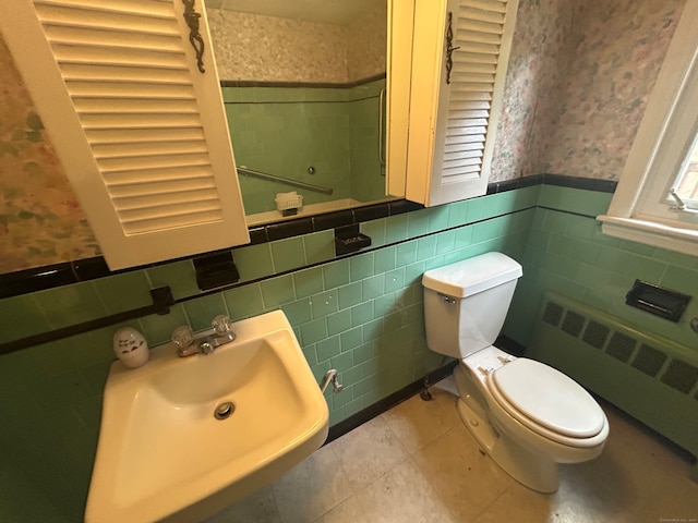 bathroom featuring radiator heating unit, tile walls, sink, and toilet