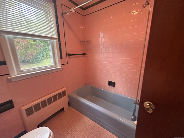 bathroom with radiator heating unit, tiled shower / bath combo, and toilet