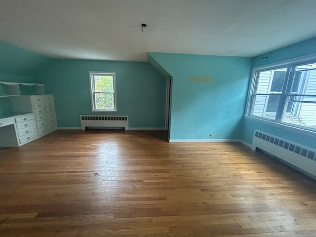 bonus room featuring radiator heating unit and hardwood / wood-style flooring