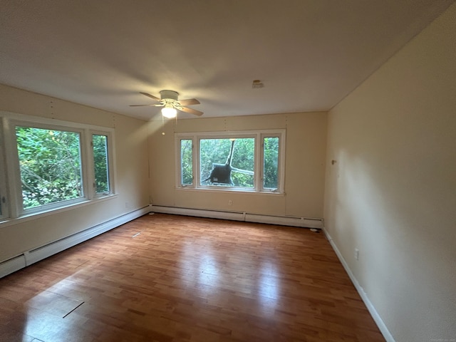 unfurnished room featuring baseboard heating, hardwood / wood-style floors, and ceiling fan