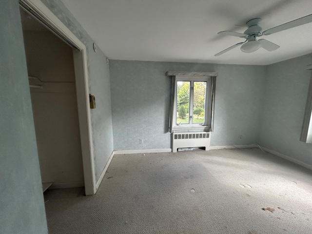 carpeted spare room with radiator heating unit and ceiling fan