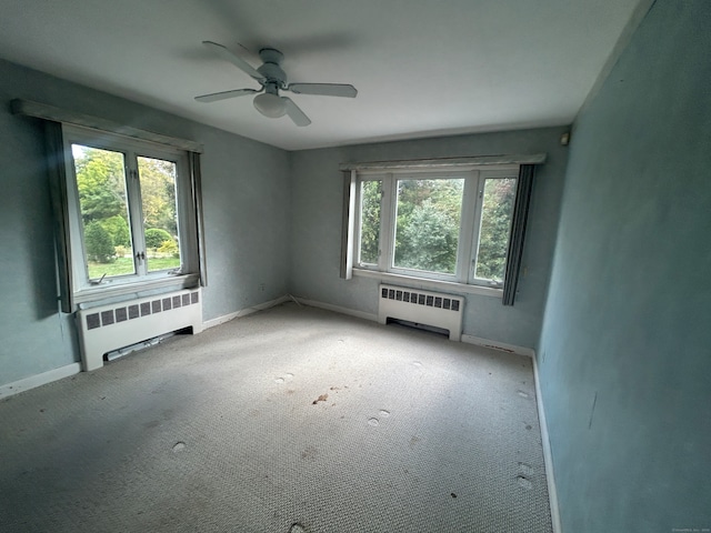 unfurnished room featuring radiator, light carpet, and ceiling fan