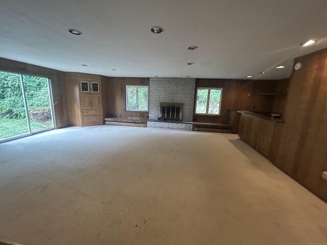 1920 Hartford Tpke, North Haven, CT 06473 - unfurnished living room with light colored carpet, wood walls, a brick fireplace, and recessed lighting