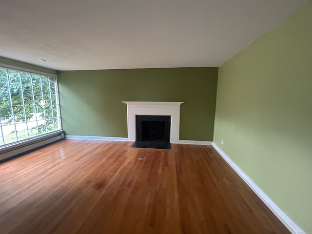 unfurnished living room with hardwood / wood-style flooring and a baseboard heating unit