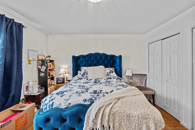 bedroom featuring hardwood / wood-style flooring, a textured ceiling, and a closet