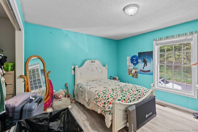 bedroom featuring light hardwood / wood-style floors and a textured ceiling