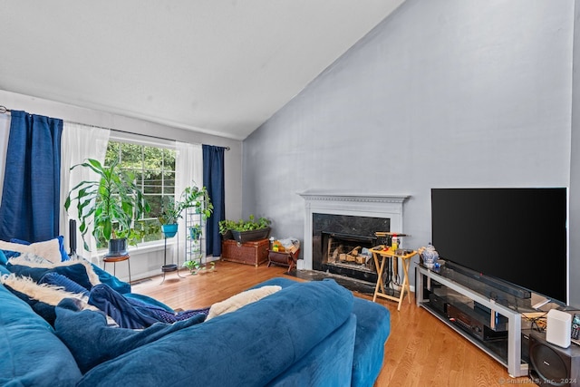 living room featuring vaulted ceiling, a premium fireplace, and light hardwood / wood-style flooring