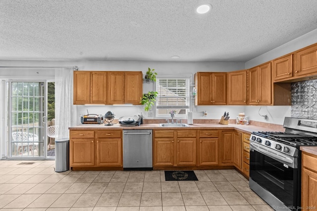 kitchen featuring a textured ceiling, light tile patterned floors, sink, and appliances with stainless steel finishes