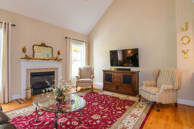 living room featuring a tile fireplace, hardwood / wood-style flooring, and high vaulted ceiling