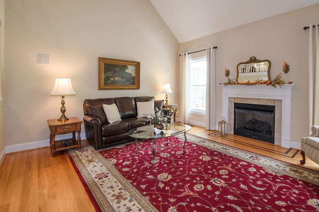 living room featuring high vaulted ceiling, light hardwood / wood-style flooring, and a fireplace