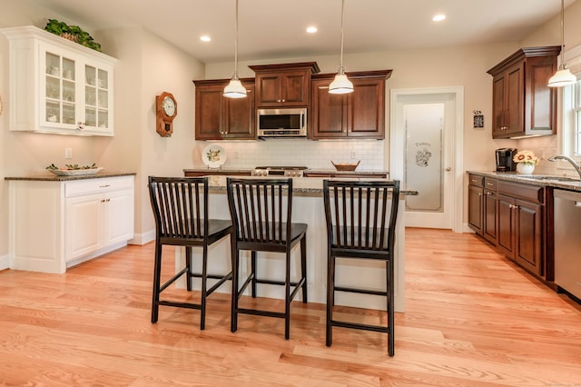 kitchen with sink, light hardwood / wood-style flooring, a kitchen breakfast bar, and stainless steel appliances