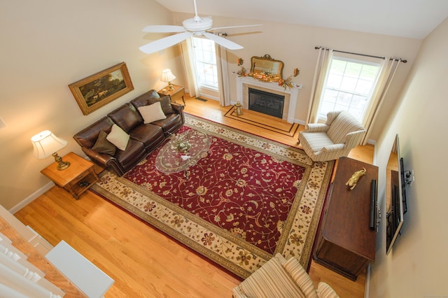 living room with ceiling fan, lofted ceiling, and light wood-type flooring