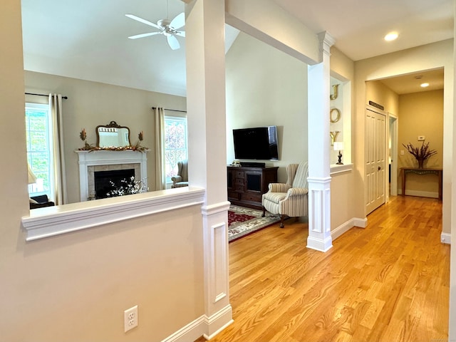 living room with light wood-type flooring, plenty of natural light, a fireplace, and ceiling fan