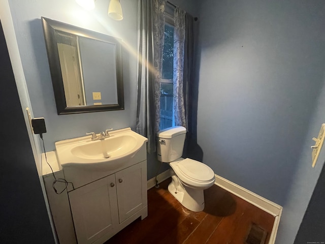 bathroom with wood-type flooring, vanity, and toilet