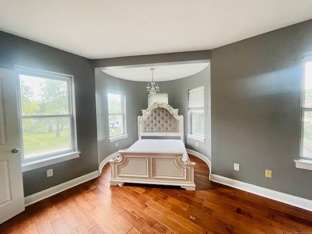 bedroom featuring a notable chandelier, multiple windows, and hardwood / wood-style floors