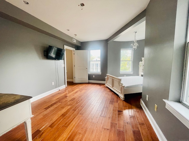 unfurnished bedroom featuring a notable chandelier and light hardwood / wood-style floors