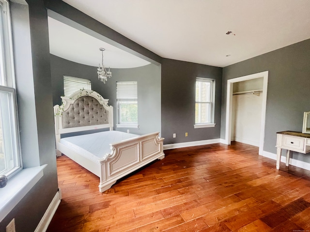 unfurnished bedroom featuring a closet, a chandelier, and wood-type flooring