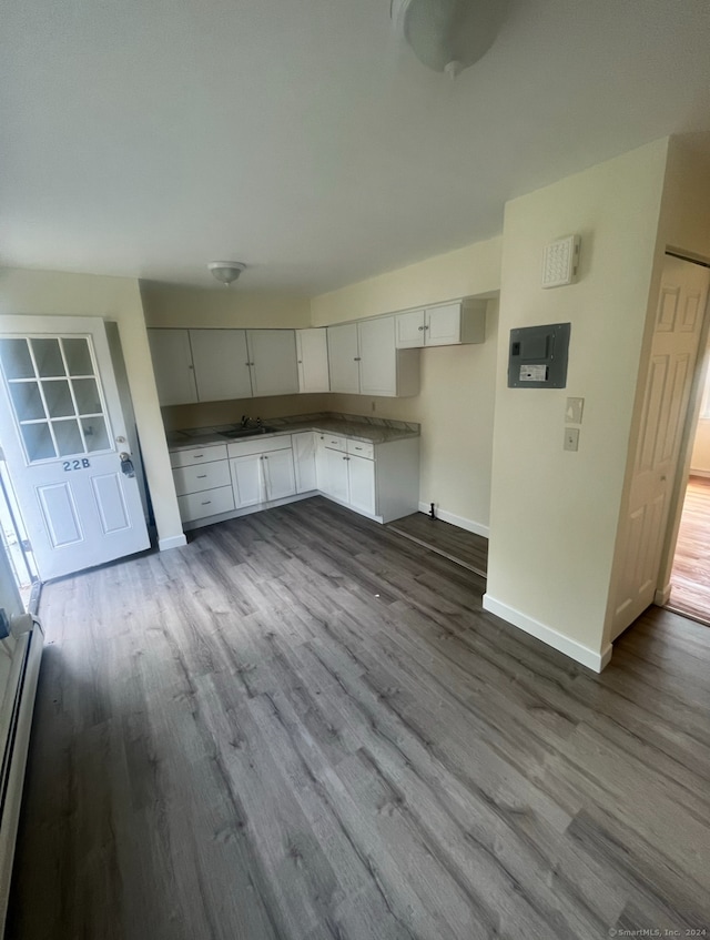 kitchen featuring white cabinetry, light hardwood / wood-style floors, baseboard heating, and sink