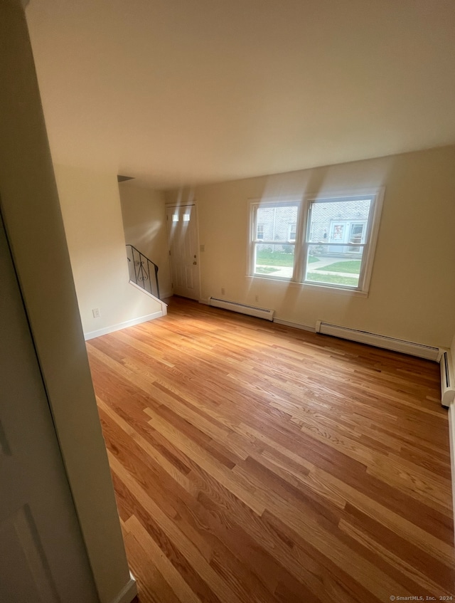 unfurnished living room featuring light wood-type flooring and baseboard heating