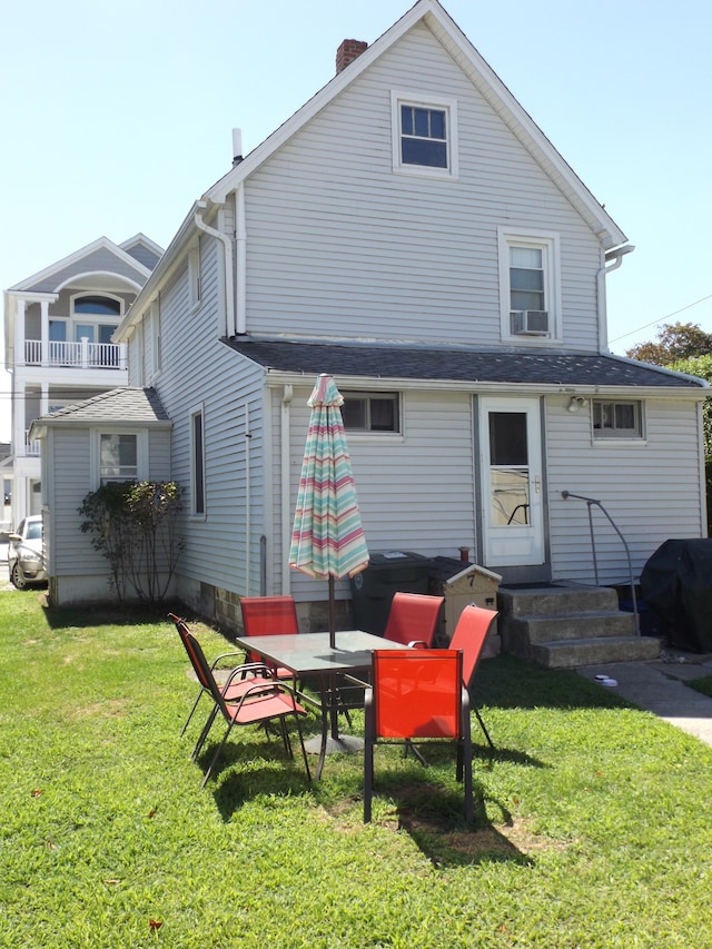 rear view of house featuring cooling unit, a balcony, a lawn, and a patio area