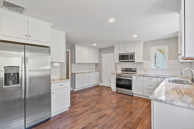 kitchen featuring sink, white cabinetry, appliances with stainless steel finishes, dark hardwood / wood-style flooring, and decorative backsplash