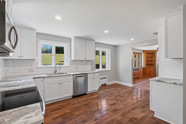 kitchen with appliances with stainless steel finishes, dark wood-type flooring, white cabinets, light stone countertops, and sink