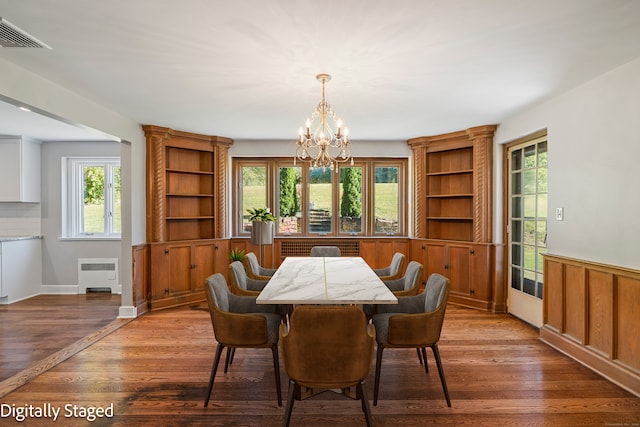 dining room featuring radiator, hardwood / wood-style flooring, plenty of natural light, and a chandelier