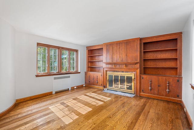 unfurnished living room featuring light wood-type flooring and radiator heating unit