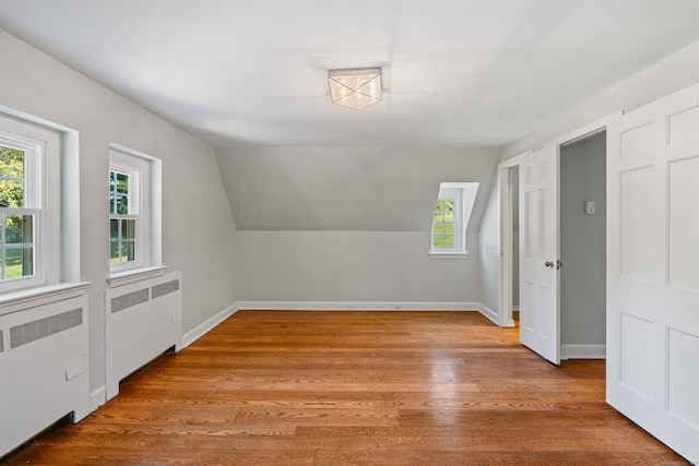 bonus room featuring vaulted ceiling, light hardwood / wood-style floors, and radiator heating unit