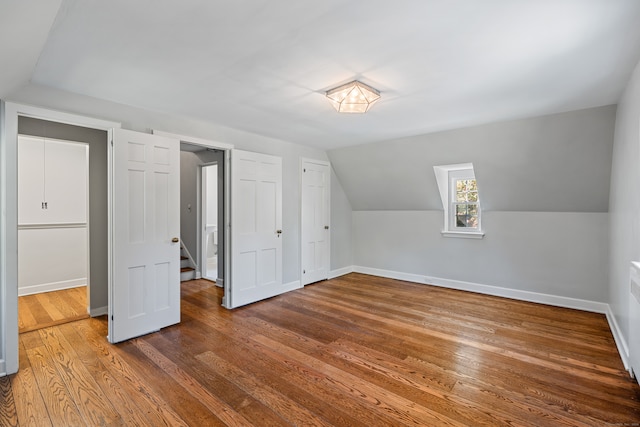 additional living space featuring wood-type flooring and vaulted ceiling