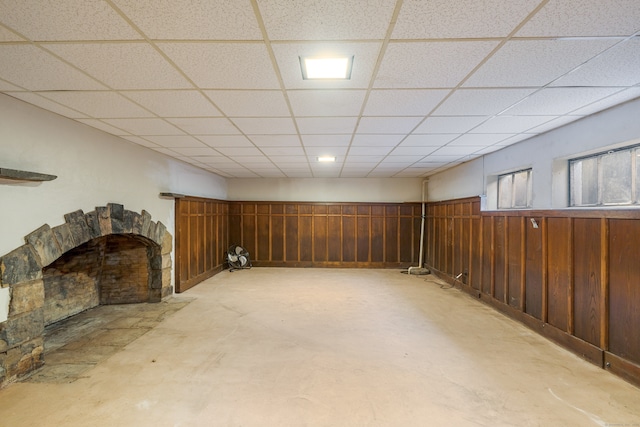 basement featuring a drop ceiling and wood walls