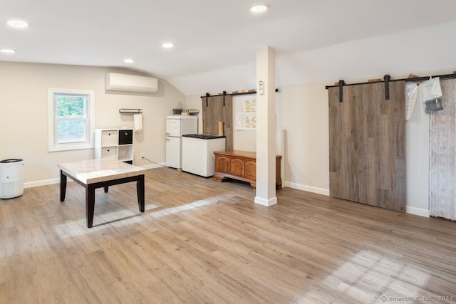 kitchen with vaulted ceiling, a barn door, a wall unit AC, and light hardwood / wood-style flooring