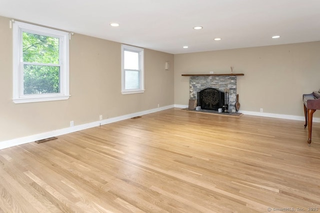 unfurnished living room with light hardwood / wood-style flooring, a fireplace, and plenty of natural light