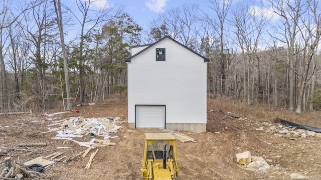 view of property exterior with a garage and a wooded view