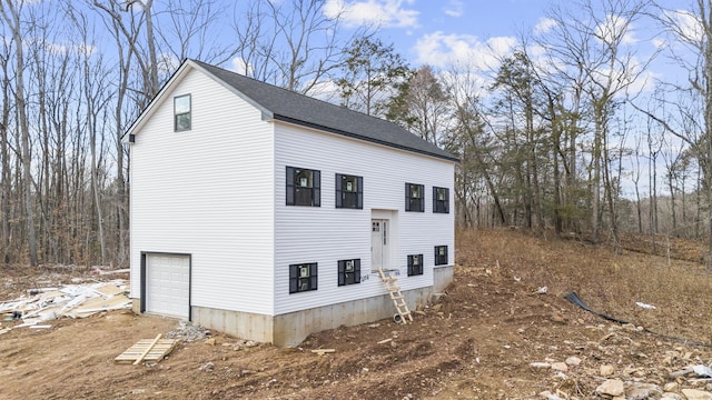 view of home's exterior with a garage and roof with shingles