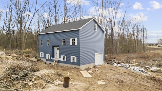 view of side of property with roof with shingles and an attached garage