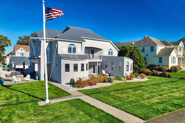 rear view of property featuring a patio area, a balcony, and a yard