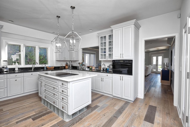 kitchen with a healthy amount of sunlight, light hardwood / wood-style flooring, a kitchen island, and black appliances