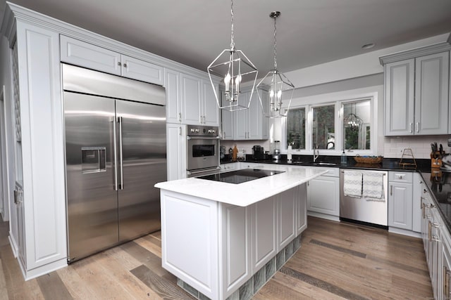 kitchen with pendant lighting, a center island, light wood-type flooring, and stainless steel appliances