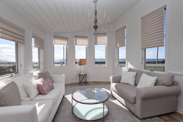 372 Maple Ave, Old Saybrook, CT 06475 - living room with a chandelier, wood finished floors, plenty of natural light, vaulted ceiling, and a wainscoted wall