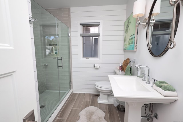 bathroom with wooden walls, a shower with door, and toilet