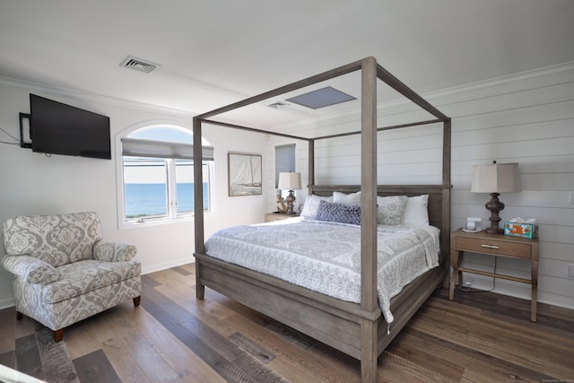 bedroom with wood walls, crown molding, and dark wood-type flooring