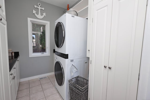 clothes washing area with light tile patterned floors and stacked washing maching and dryer