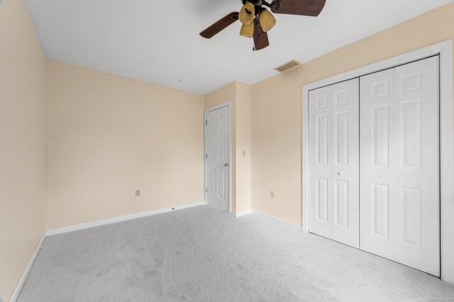 unfurnished bedroom featuring a closet, light colored carpet, and ceiling fan