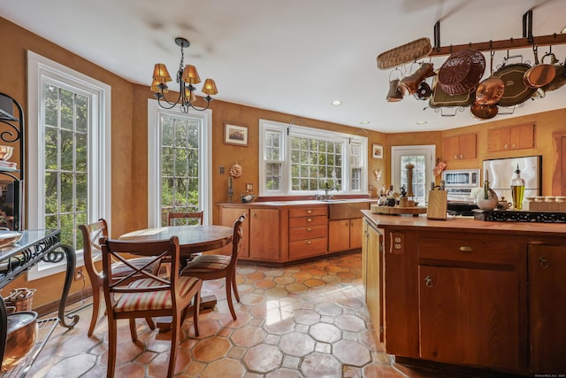 kitchen featuring recessed lighting, appliances with stainless steel finishes, brown cabinets, decorative light fixtures, and an inviting chandelier