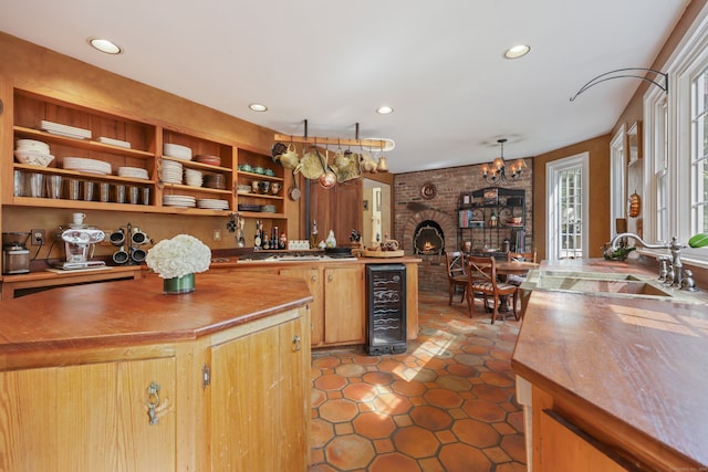 kitchen featuring sink, wine cooler, a fireplace, a notable chandelier, and dark tile patterned flooring