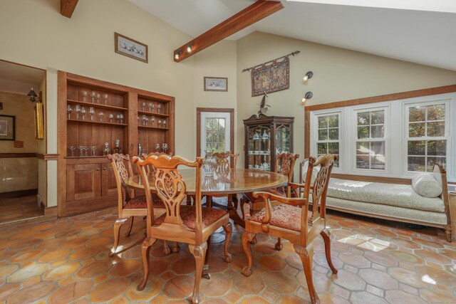 tiled dining space with beam ceiling and high vaulted ceiling