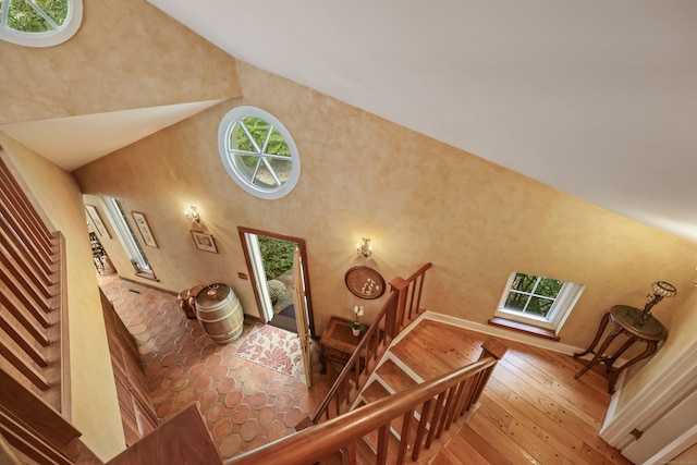 stairs with high vaulted ceiling and wood-type flooring