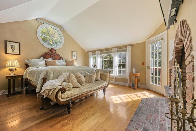 bedroom featuring access to exterior, light hardwood / wood-style flooring, multiple windows, and lofted ceiling