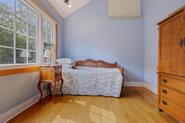 bedroom featuring lofted ceiling, light wood finished floors, and baseboards